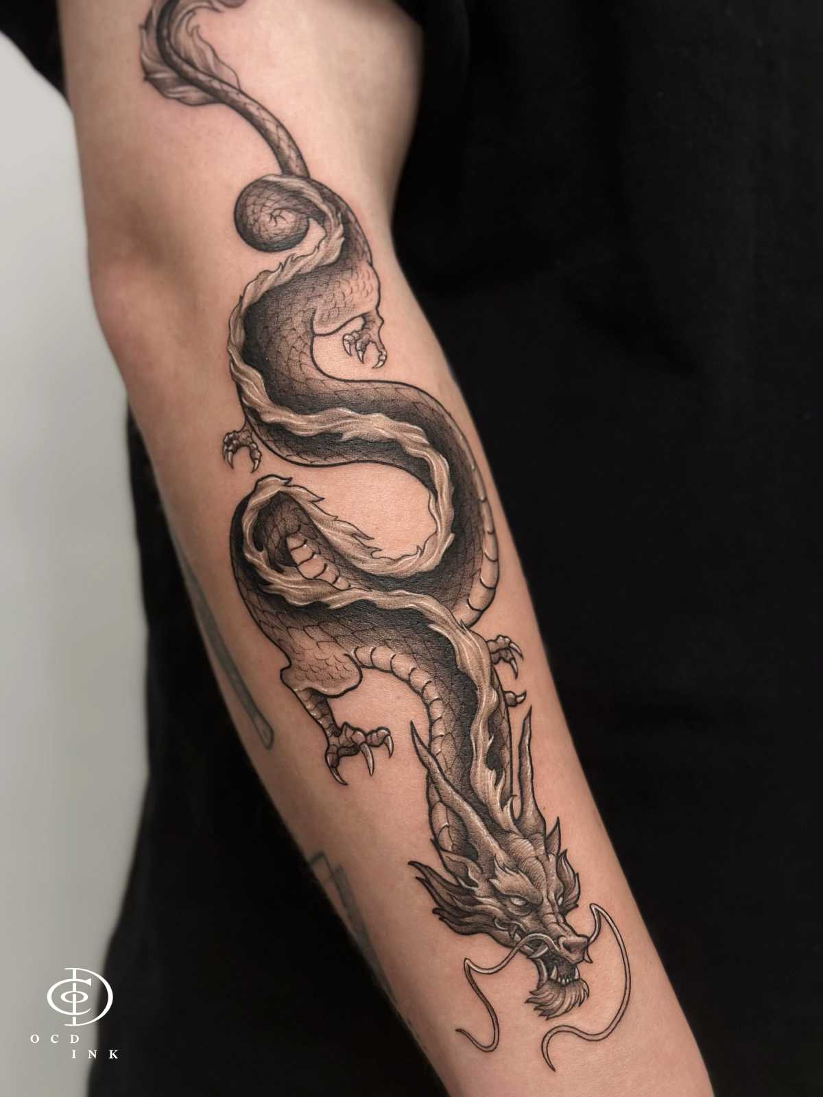 a black and grey asian dragon tattoo on the arm by OCD Ink Studio in Hanoi
