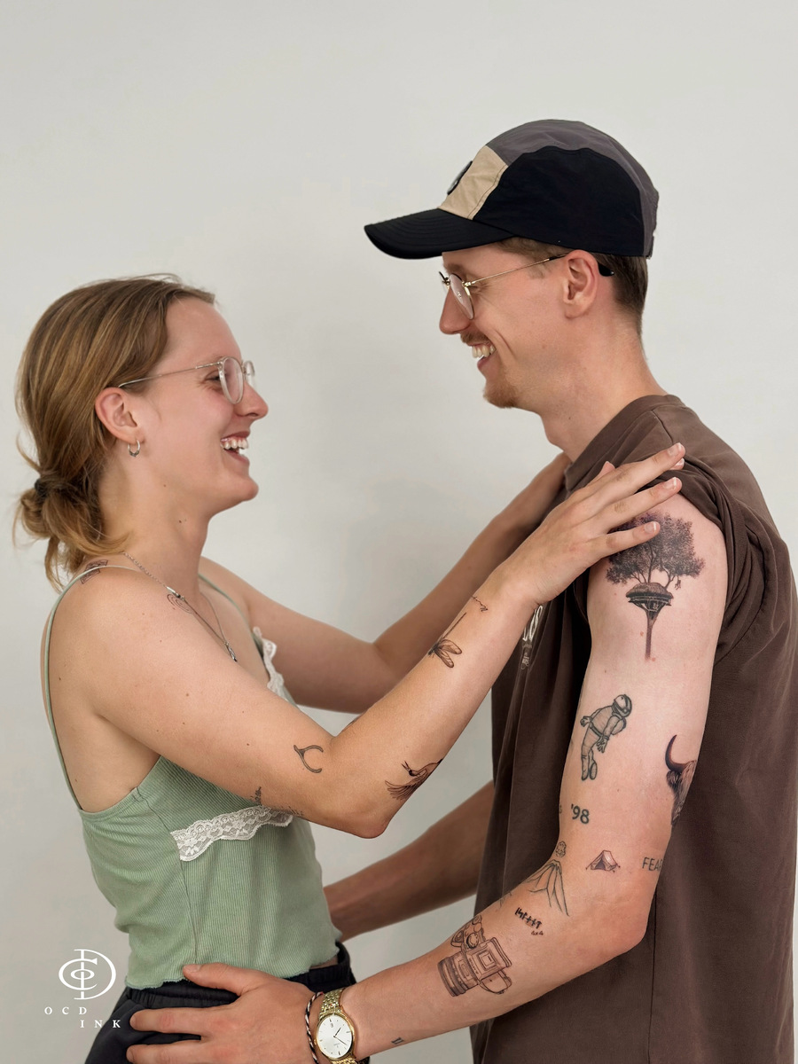 A happy couple at OCD Ink Studio; the man displays a detailed black and grey realism tree tattoo.