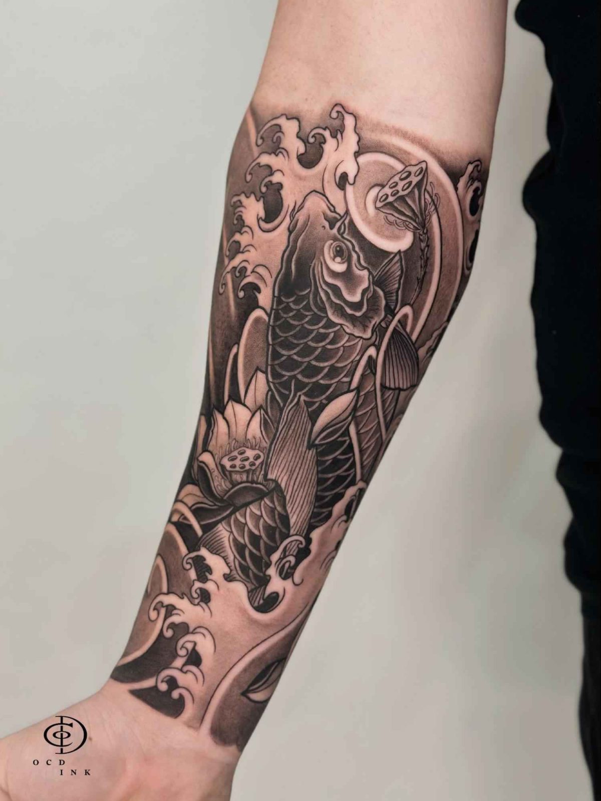 Blackwork Japanese-style blackwork oriental tattoo featuring a koi fish swimming through lotus flowers and waves