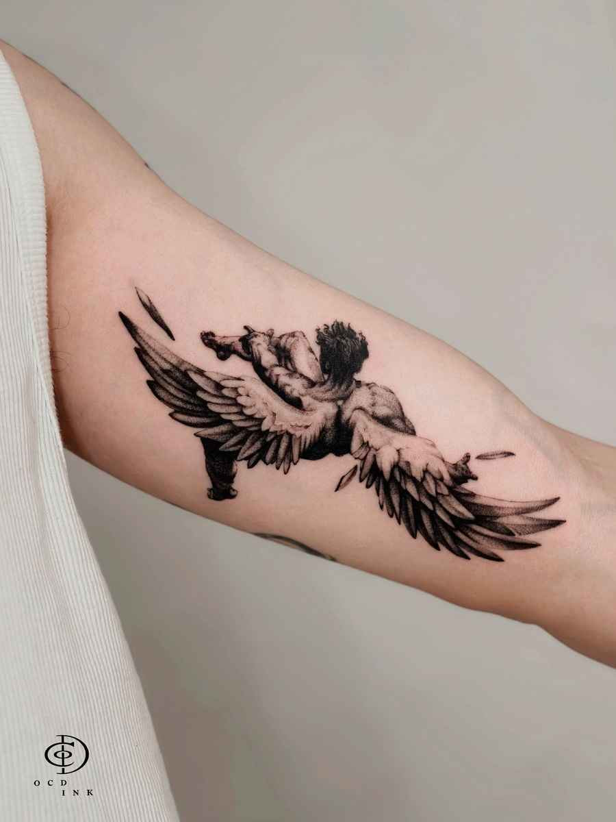 Blackwork Blackwork tattoo of a fallen angel with spread wings, realistic shading, and dynamic motion on the forearm