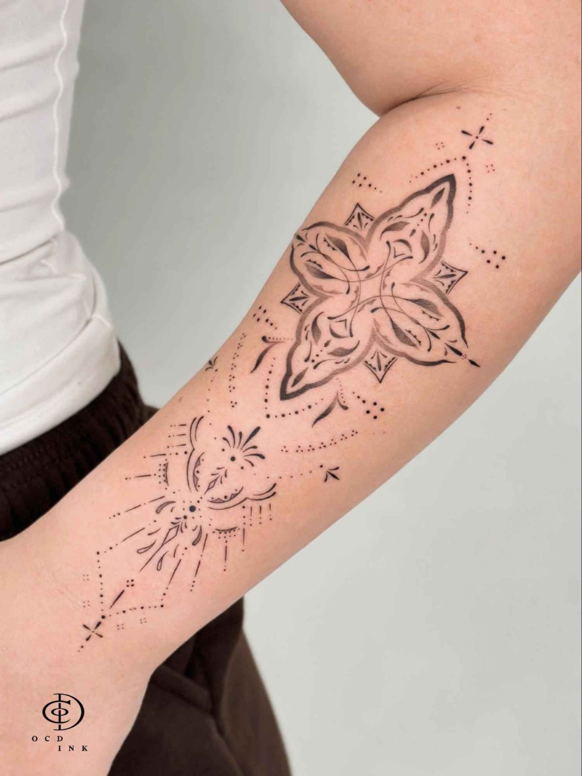 Flower ornamental tattoo featuring a stylized floral mandala with fine-line details and decorative dotwork on the forearm
