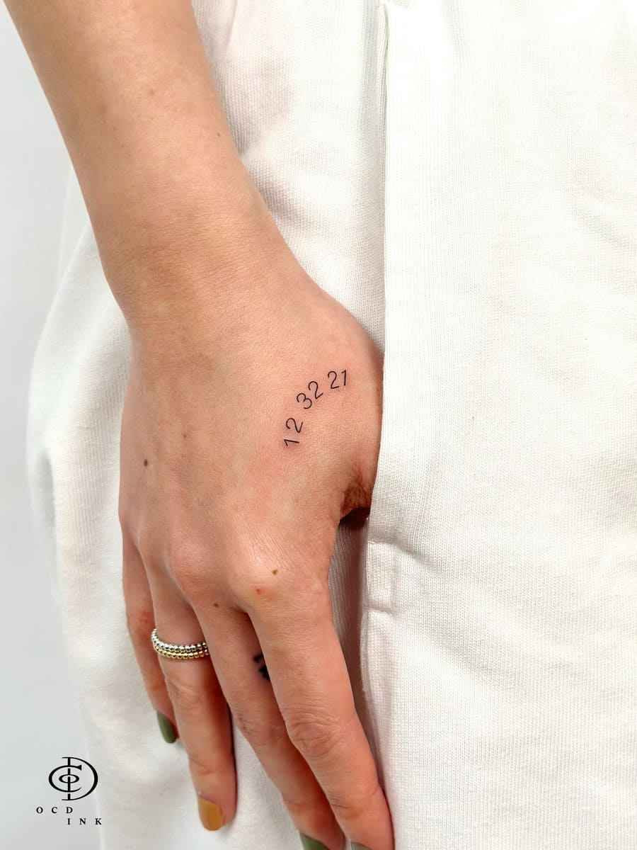 Minimalist fine line number tattoo featuring a meaningful date on the hand