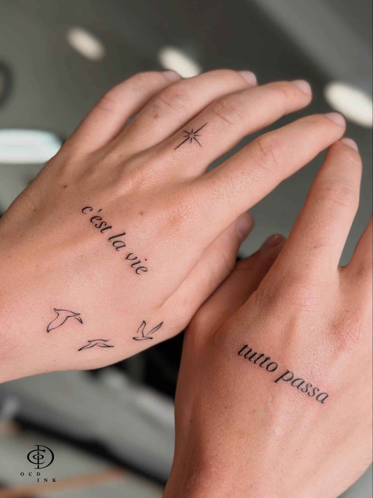 Minimal serif font tattoos with Italian and French phrases on the hands