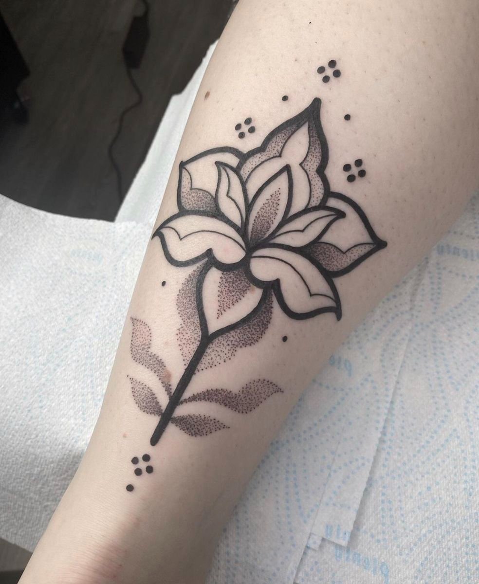 Hybrid dotwork tattoo of a stylized lily on the forearm, combining bold blackwork outlines, smooth stipple shading, ornamental floral details, and modern illustrative design.