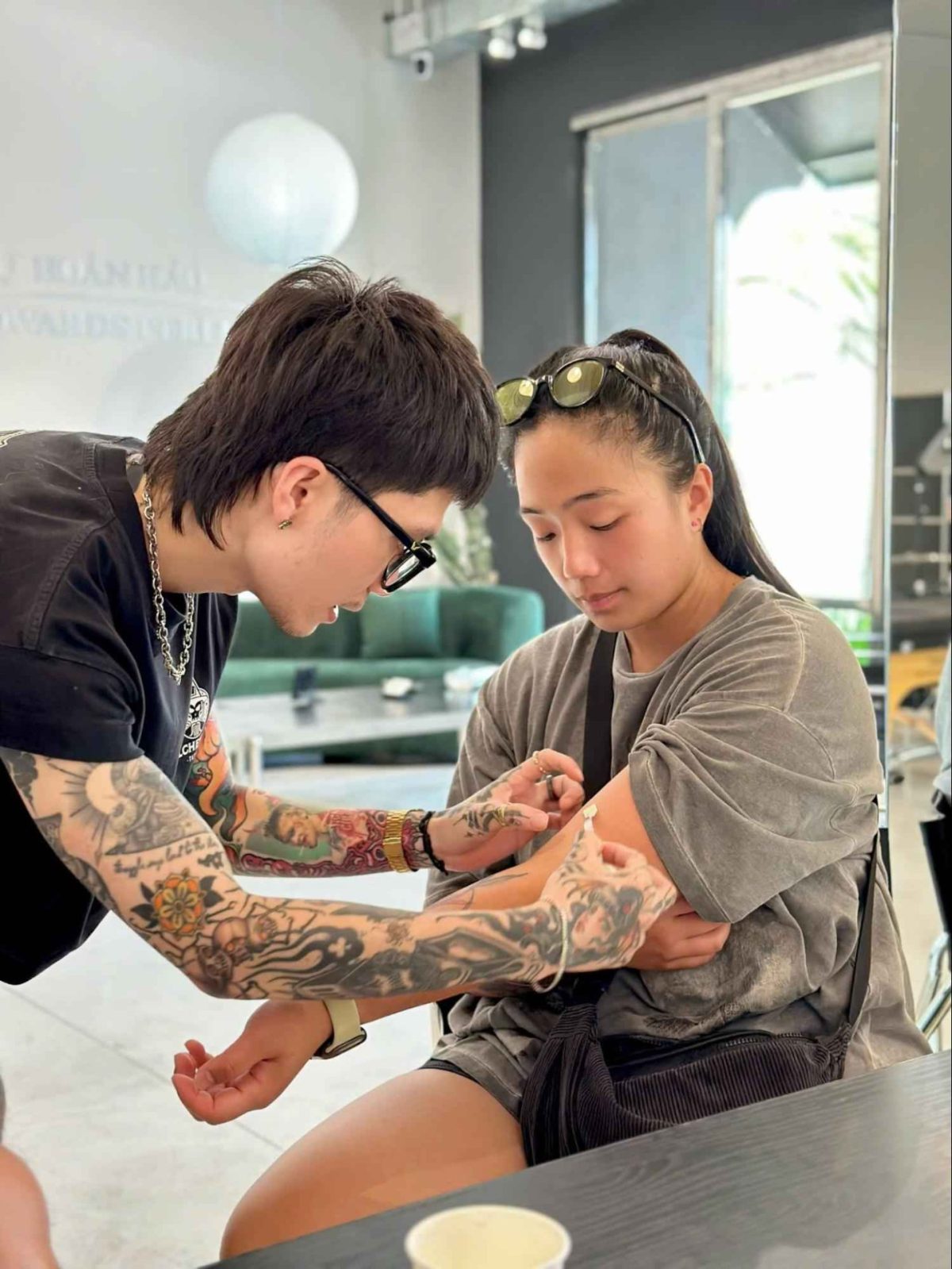 Professional tattoo artist applying a stencil and discussing placement with a client before a tattoo session in a modern tattoo studio.