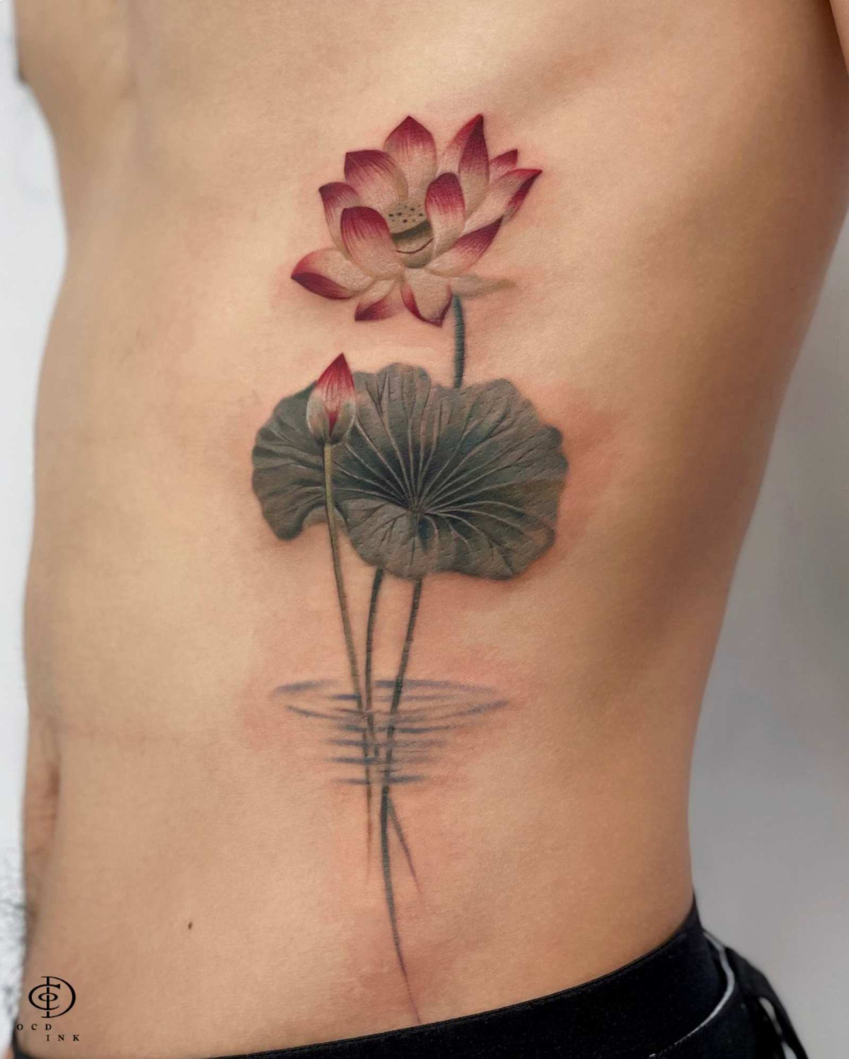 COLOR Color lotus flower tattoo featuring pink blossoms, large green leaves, and soft water ripple details in a realistic Asian-inspired botanical design.