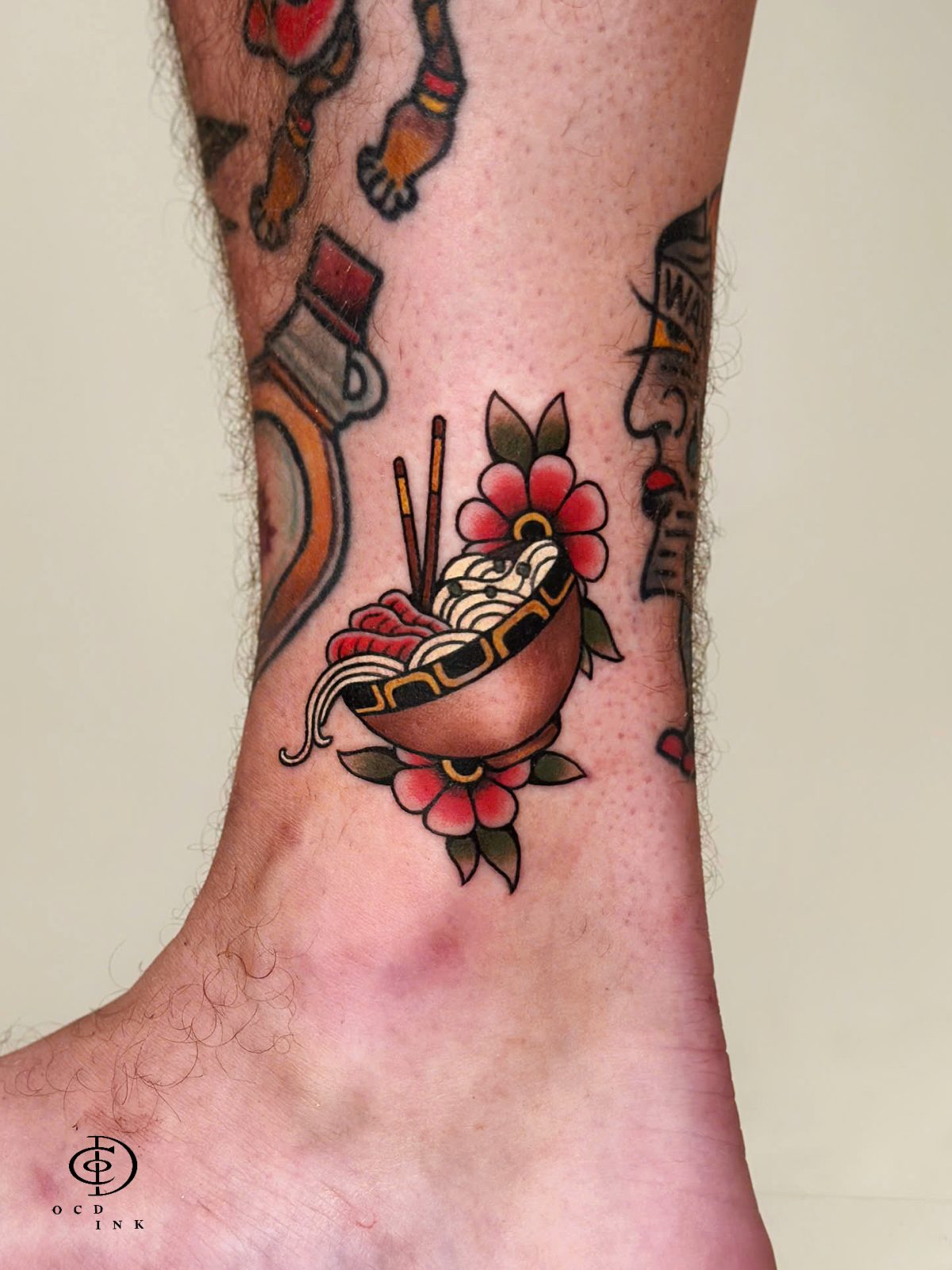 COLOR Vietnam-inspired color tattoo of a steaming bowl of pho with noodles, chopsticks, herbs, and pink flowers, designed in a bold traditional tattoo style