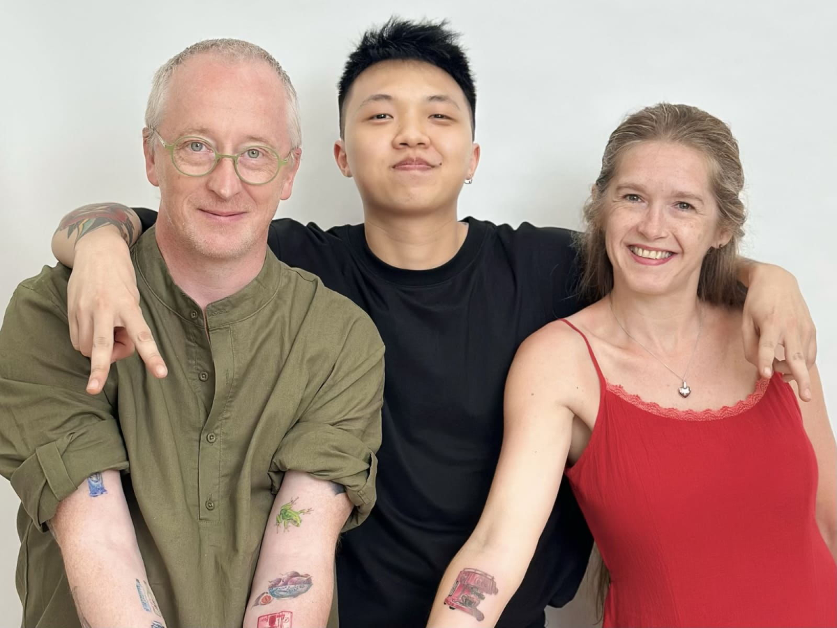 COLOR Portrait of a tattoo artist posing with two smiling clients after their tattoo session, showcasing a friendly and welcoming tattoo studio atmosphere.