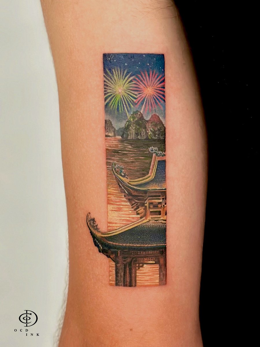 Fine art color tattoo of a Vietnamese waterscape at night featuring traditional temple rooftops, limestone karsts, calm water, and colorful fireworks inside a vertical rectangular frame.