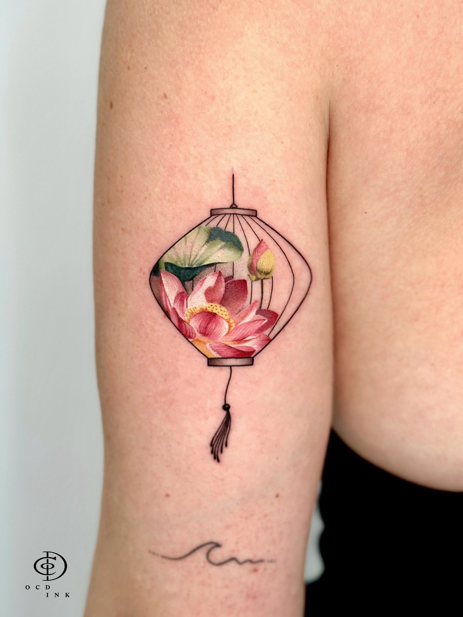 Fine art tattoo of blooming pink lotus flowers and lotus leaves enclosed within a traditional Vietnamese lantern outline, rendered with soft gradients and delicate linework.