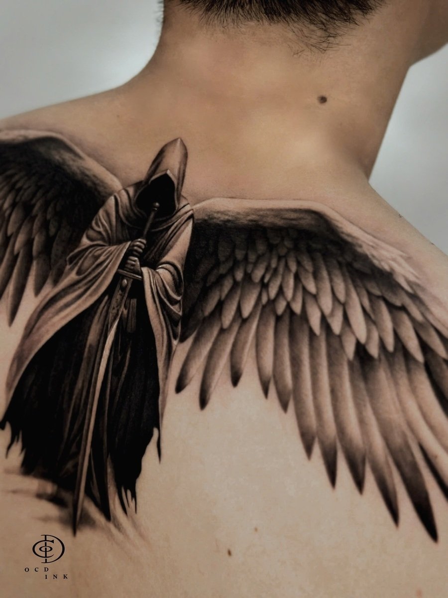 Black & Gray A large black and gray tattoo across the upper back depicting a hooded, faceless angel with expansive feathered wings