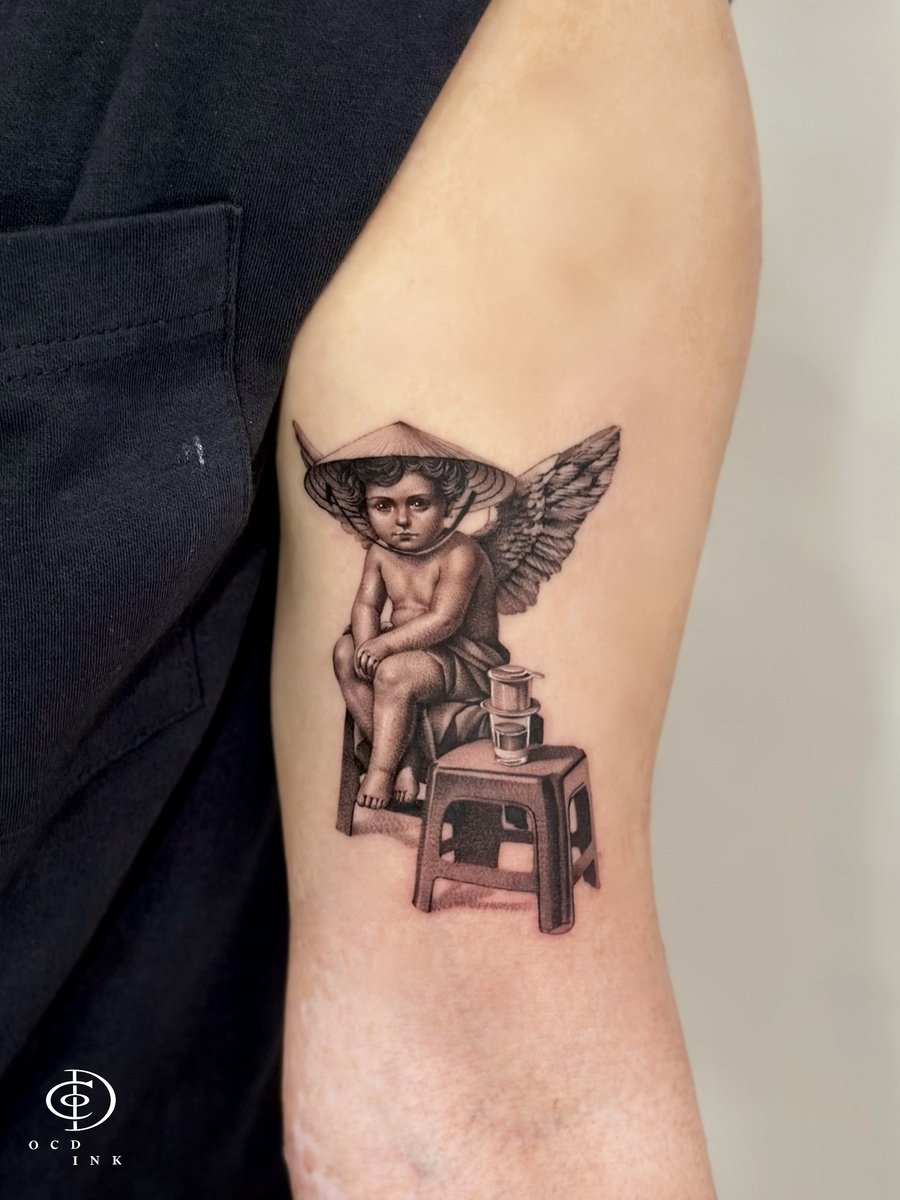 Black & Gray A Vietnam-inspired black and gray tattoo featuring a contemplative cherub seated on a small stool, wearing a traditional Vietnamese nón lá (conical hat)