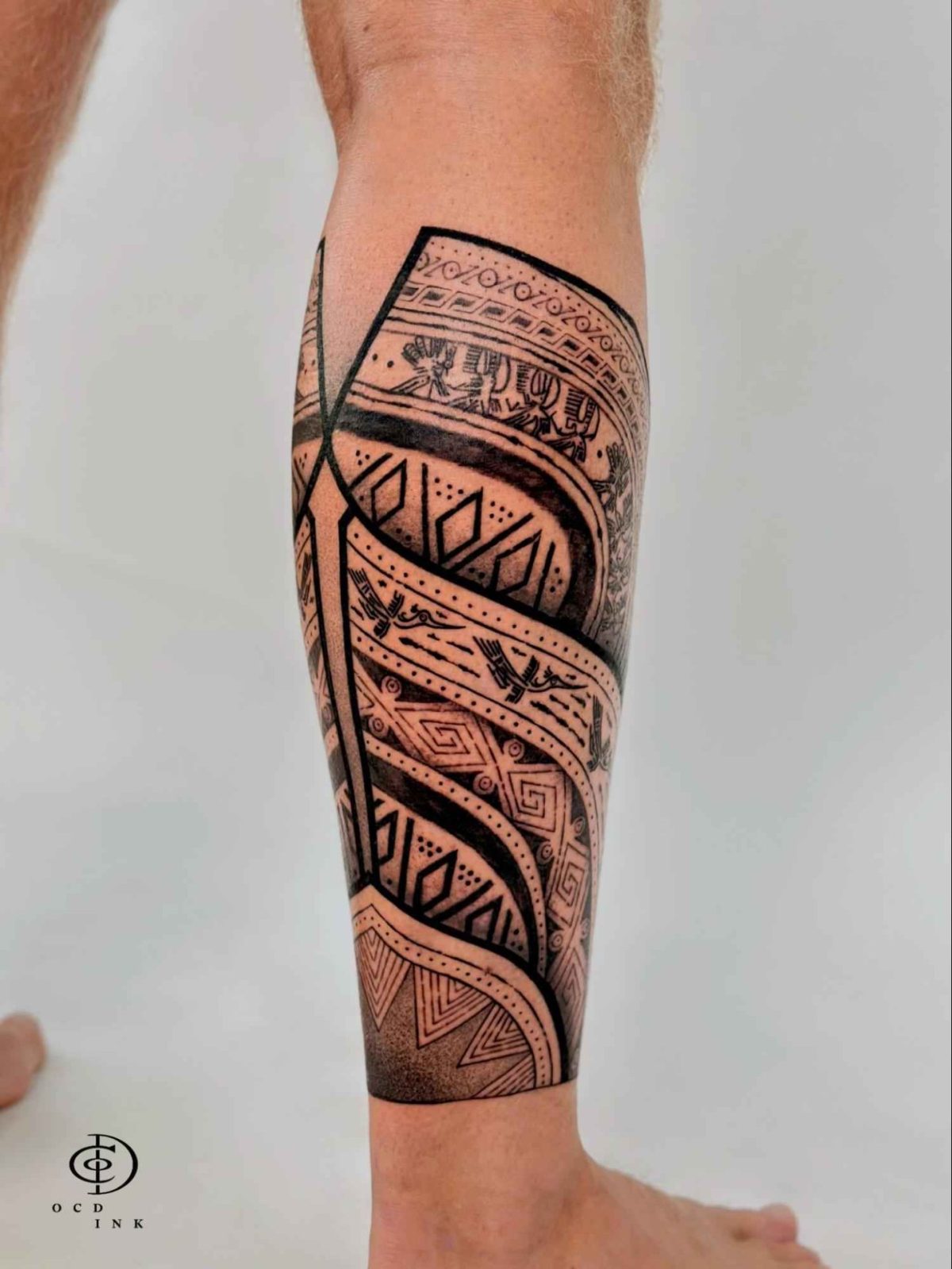 Vietnamese traditional blackwork leg tattoo featuring Đông Sơn bronze drum-inspired geometric bands, bird motifs, and intricate ornamental patterns