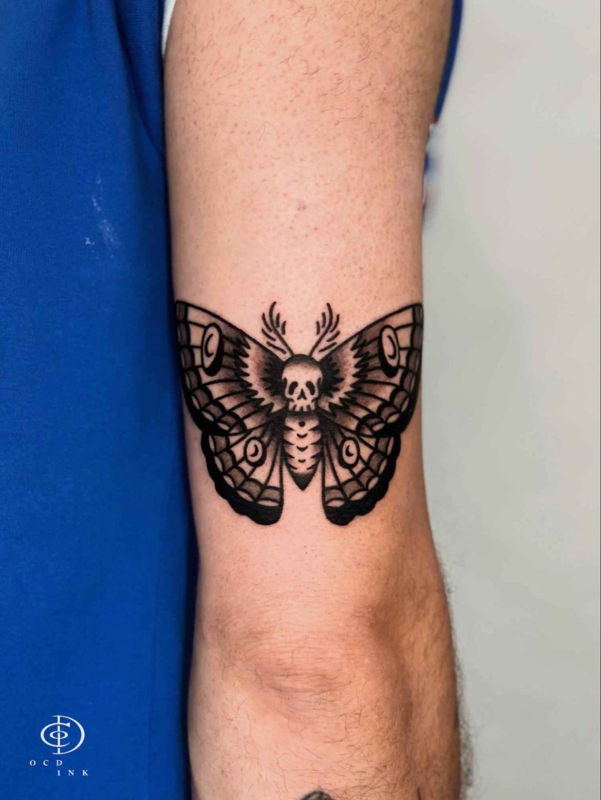 American traditional blackwork tattoo of a death’s-head moth with a skull motif and symmetrical wings on the arm