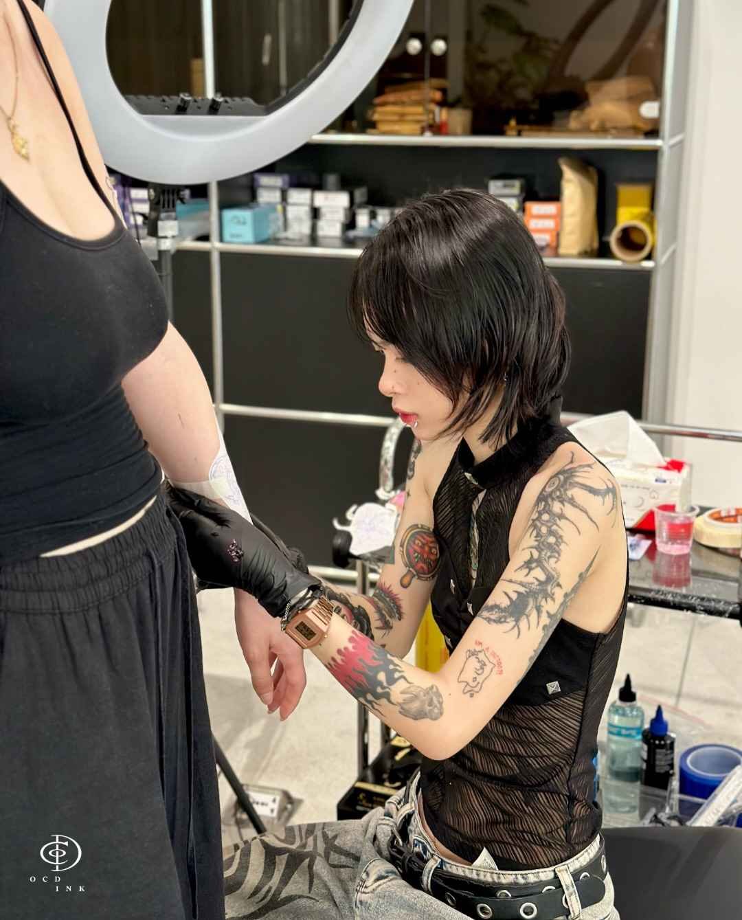 ILLUSTRATION Tattoo artist wearing black gloves prepares a client’s arm during a professional tattoo session