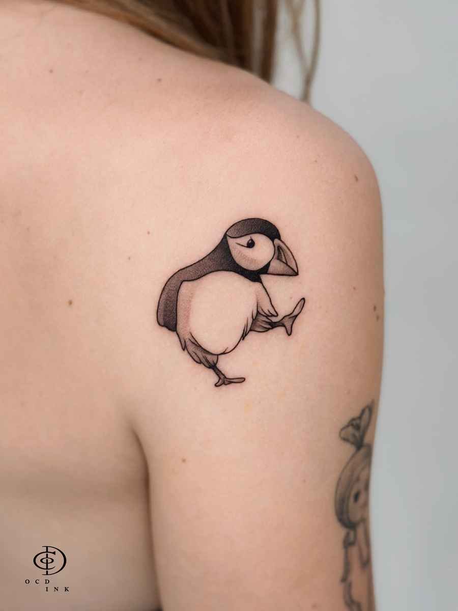 ILLUSTRATION Illustration tattoo of a playful puffin balancing on one leg on the upper back