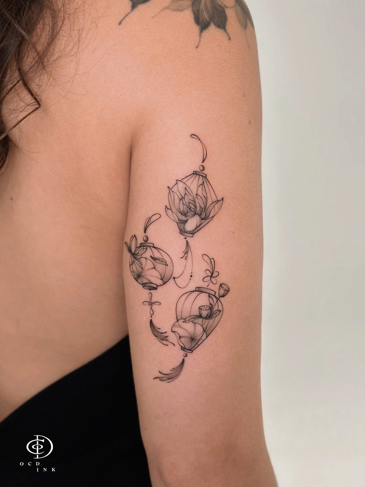 Fineline tattoo of a lotus flower and traditional lantern, featuring elegant linework, soft botanical details, and a minimalist cultural inspired composition tattoo on the arm by OCD Ink Studio in Hoi An