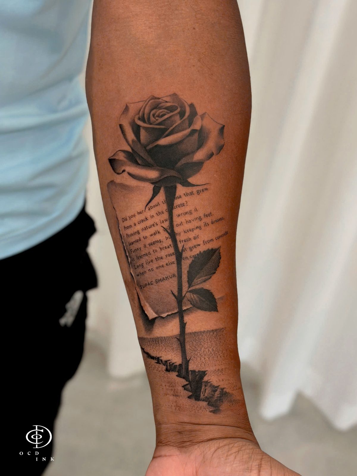 Black and gray realistic rose tattoo combined with delicate lettering, creating a meaningful floral design with a subtle personal element tattoo on the forearm by OCD Ink Studio in Hanoi